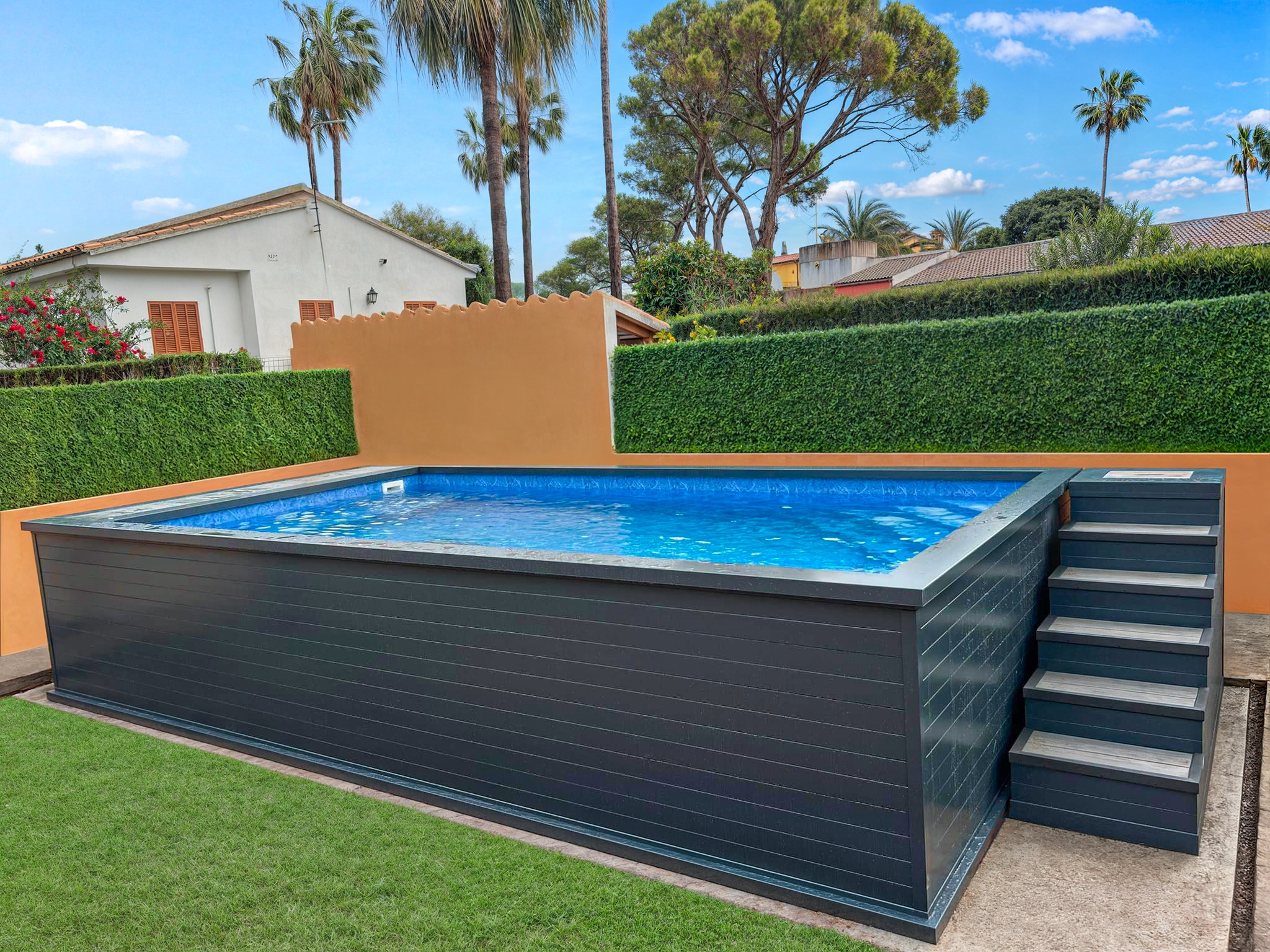 Gray above-ground aluminium pool with built-in stairs, placed in a backyard with palm trees and hedges